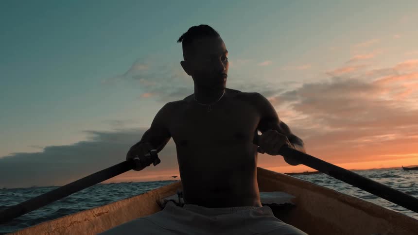 A man rows a boat at dusk