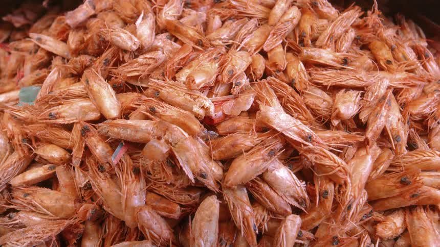 A massive pile of cooked reddishorange shrimp with their heads and shells still intact