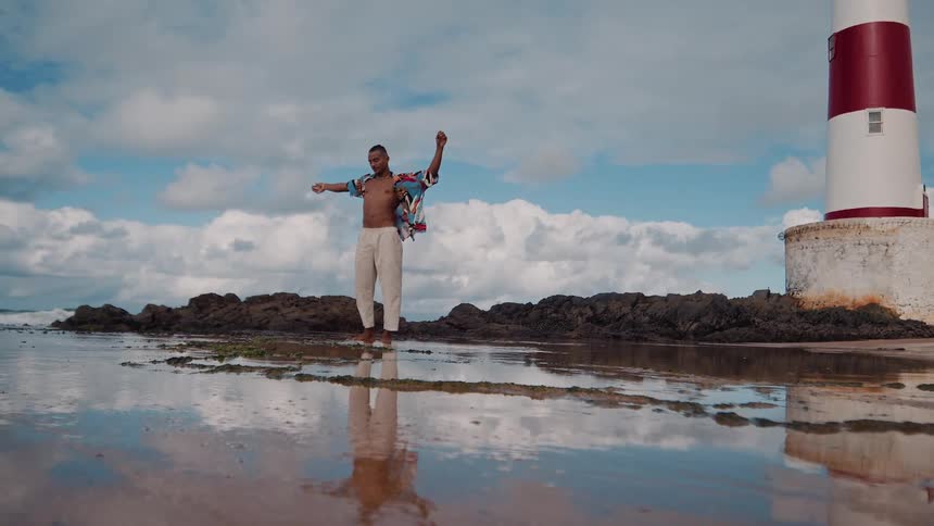 A man is waving his arms by the lighthouse