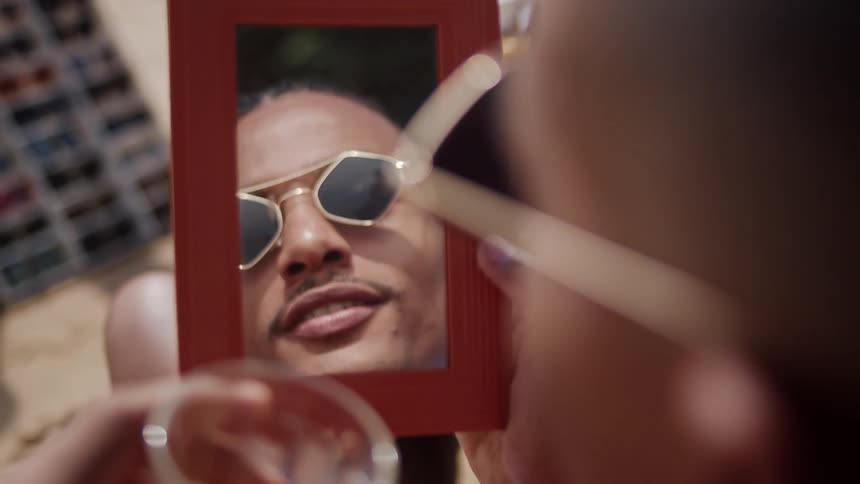 A man drinks alcohol while looking in a mirror
