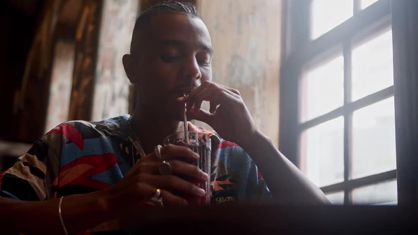 A man sips from a straw in a cozy caf by the window