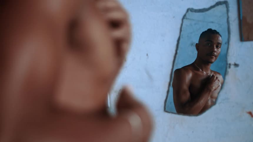 The man is rubbing his torso while looking in the mirror