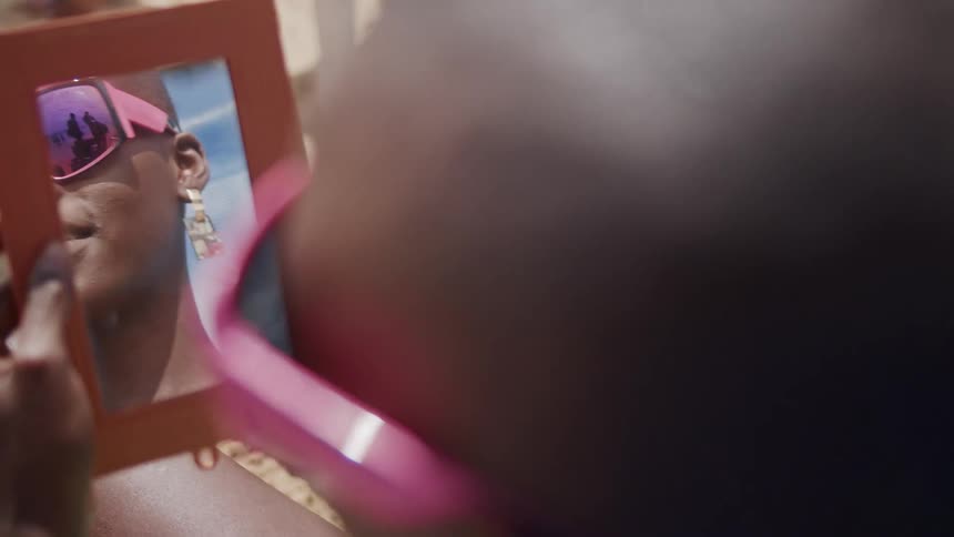The woman is checking out her sunglasses in a mirror