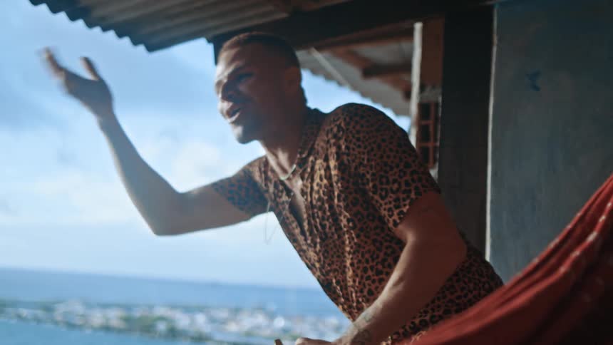 Man on balcony making hand sign with happy expression