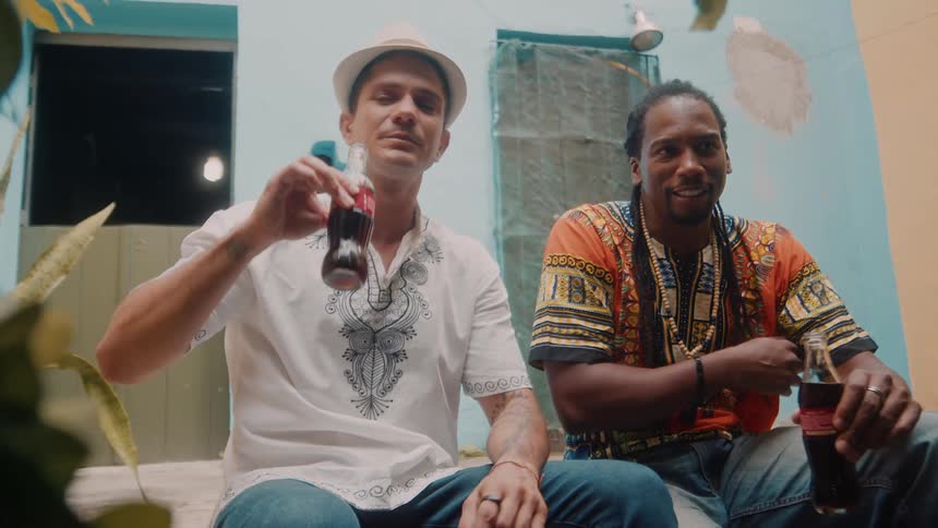 Two men are sitting together having a casual conversation while drinking soda