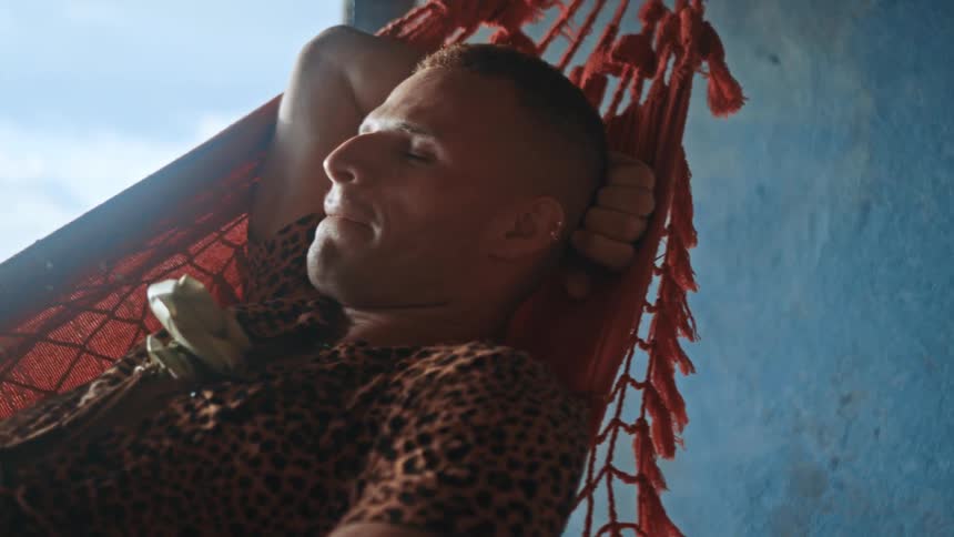 A man is laying in the hammock resting