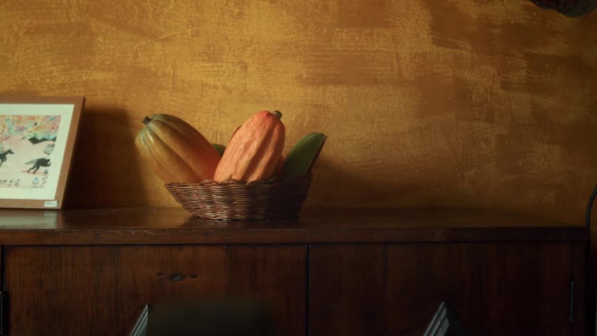 Wicker basket with cocoa pods on wooden cabinet against yellow wall