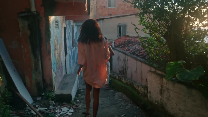 Young woman walks down a slope in a compound with friends during daytime