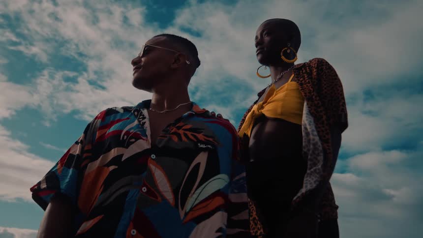 Two stylish people pose boldly under a dramatic sky