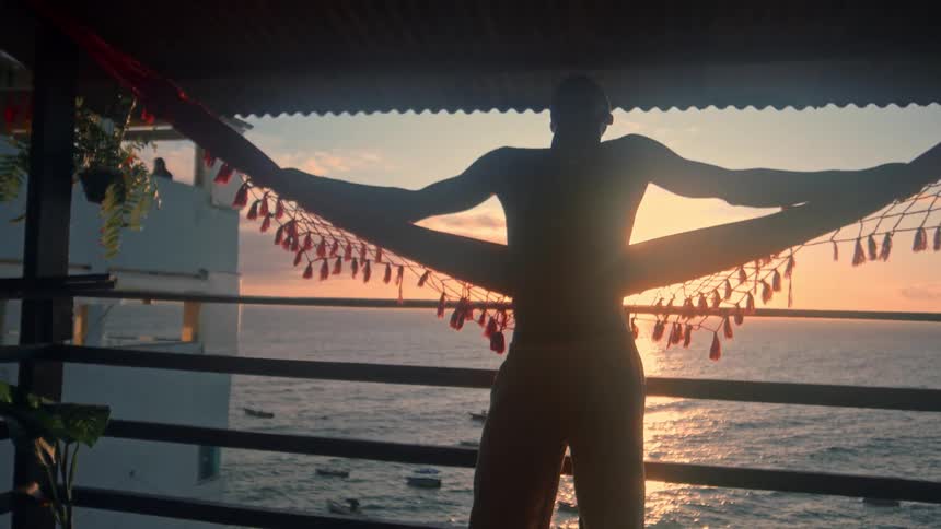 A man is standing on the balcony at sunrise