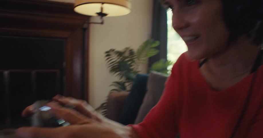 A woman playing video games on the couch in her living room at home
