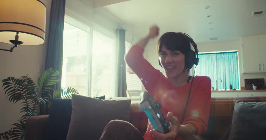The woman is using a controller and cheering as she plays
