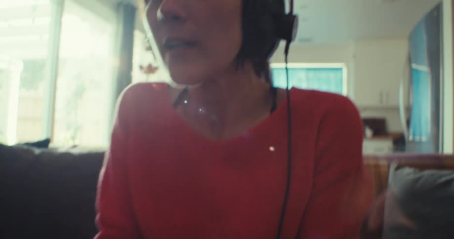 The face of a young woman wearing headphones and she is holding a video game controller and then starts celebrating