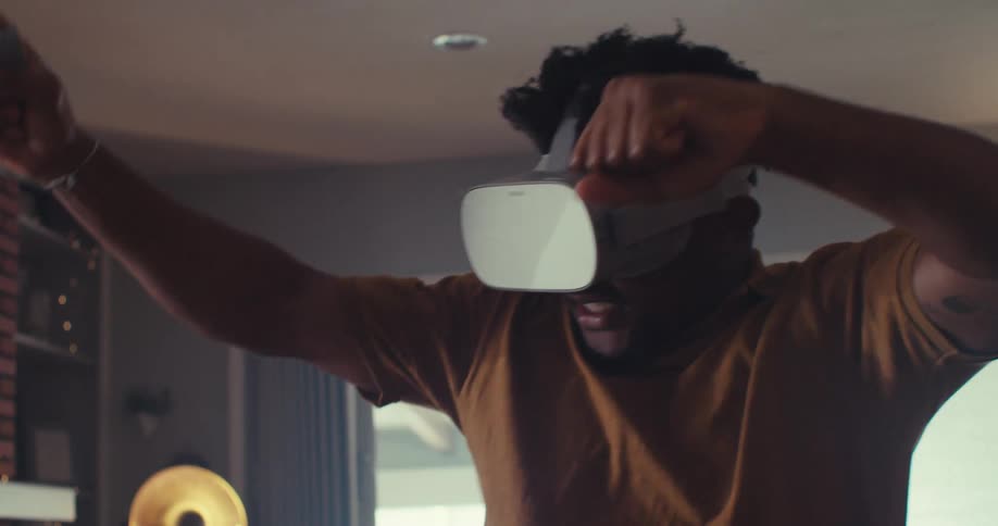 The man moves across the room playing with virtual reality