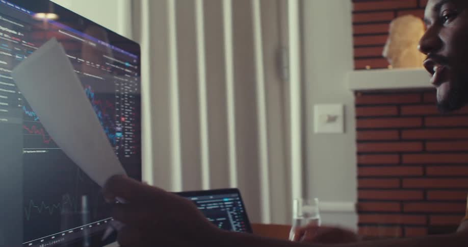 A man talks while reviewing graphs on paper and the computer screen