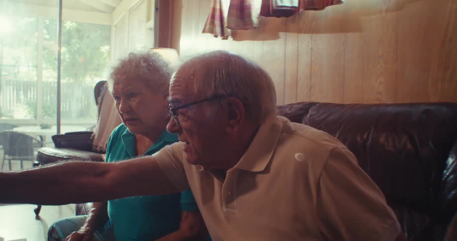 A man and woman point and talk while looking at a laptop