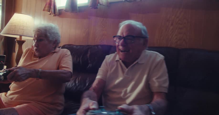 An elderly couple gaming together in their living room having fun