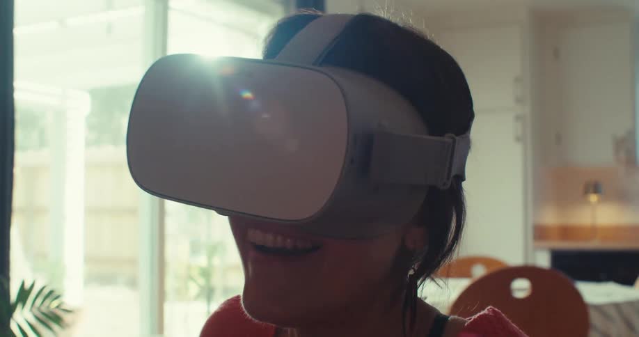 Close up of a young woman smiling while wearing virtual reality goggles indoors during daytime