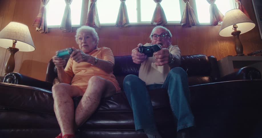 Elderly couple excitedly playing video games together on a couch