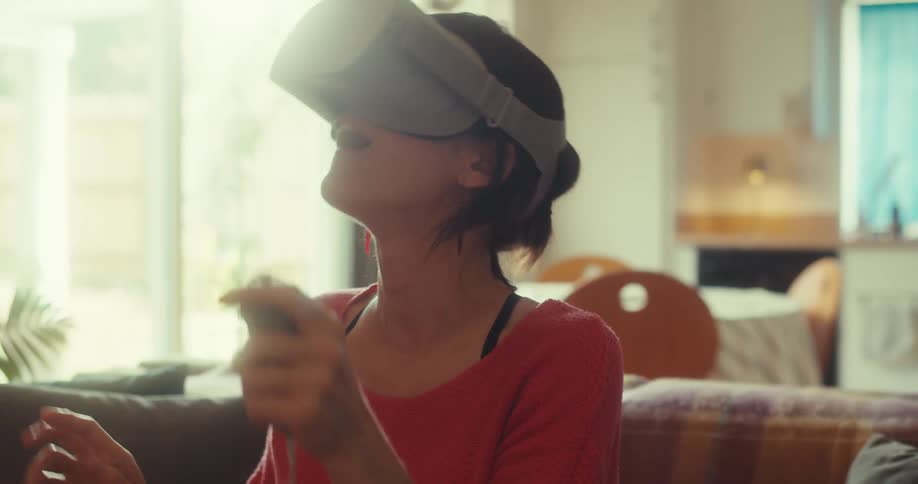 A woman is lifting a controller while using a virtual reality headset