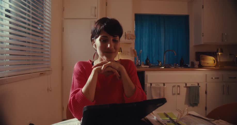A woman talks and moves her hands in front of her tablet