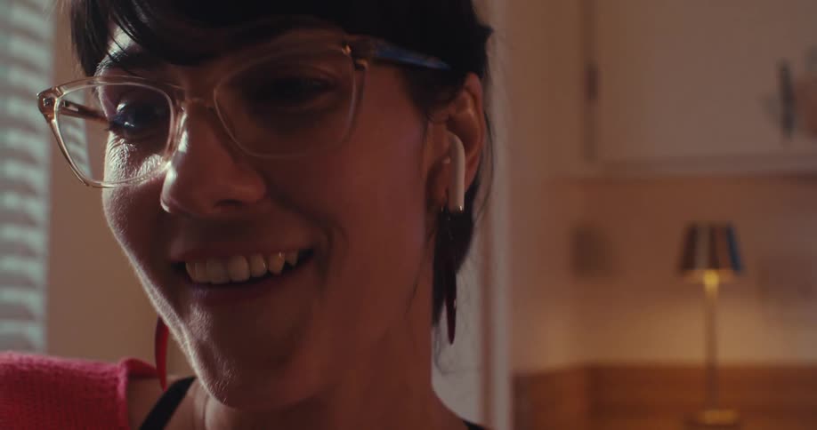 The face of a woman who is wearing reading glasses and she is talking to someone in front of her while giving subtle smiles