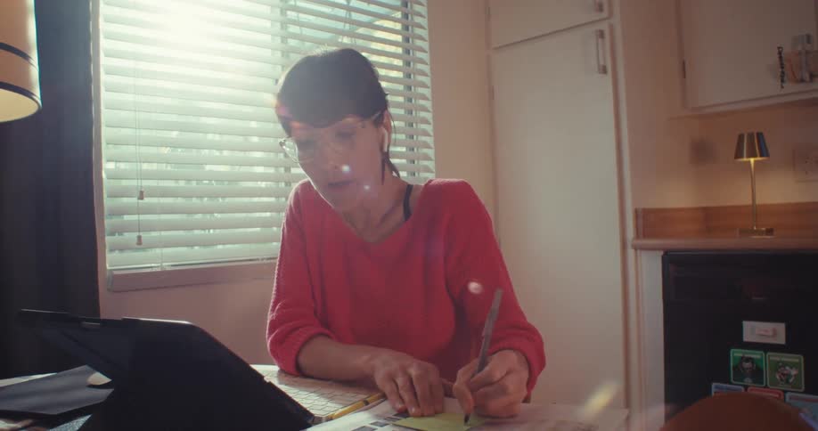 The woman is writing and talking to her tablet