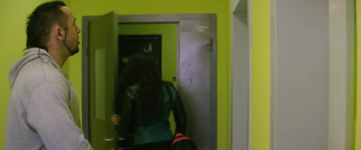 A man and woman enter a room carrying bags