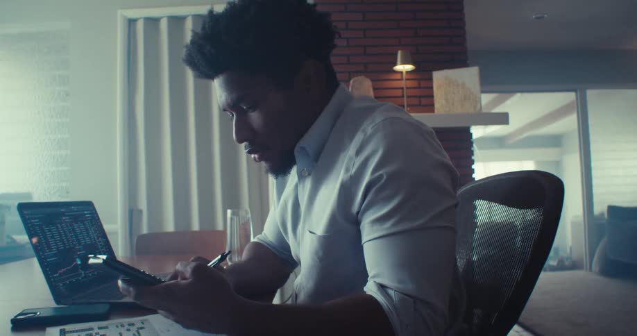 The man is using a calculator at his desk