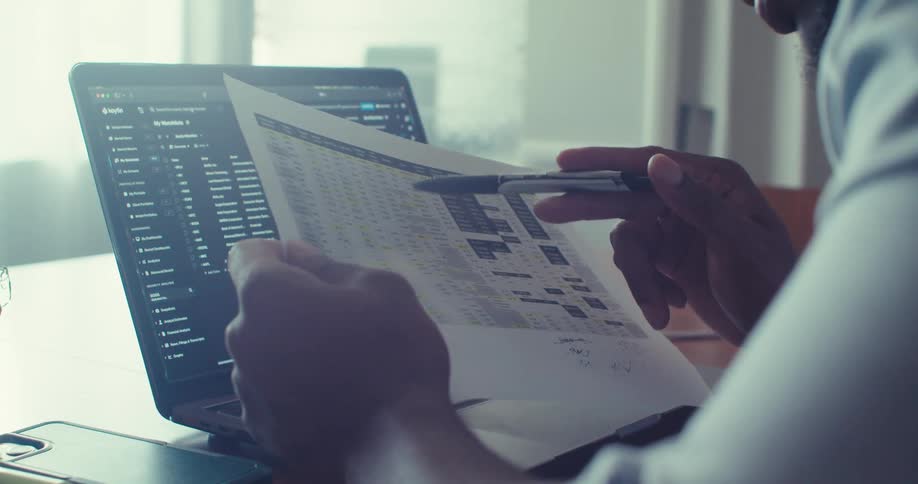 A man is reading paperwork and pointing at lines on it