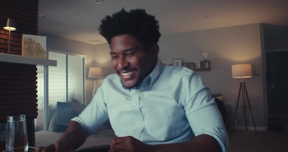A man cheers and then types on his computer