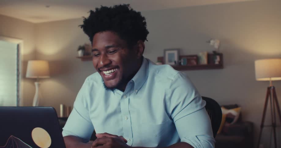 A man in his living room talking to someone through his laptop