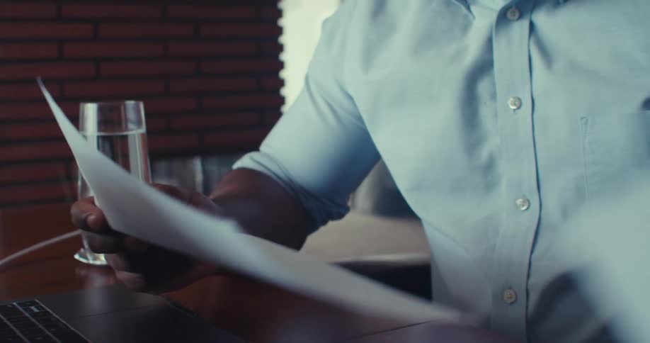 A man shuffles papers around his computer