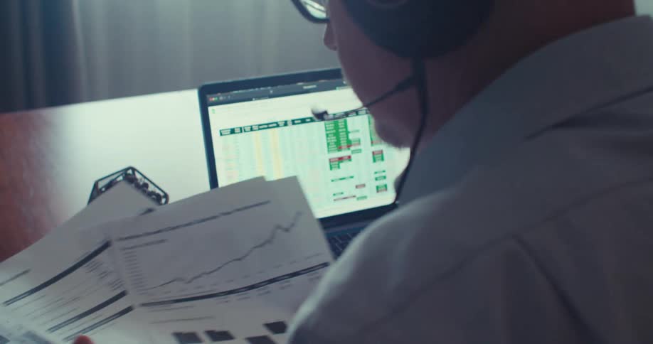 Man looks through printed documents while sitting near a computer