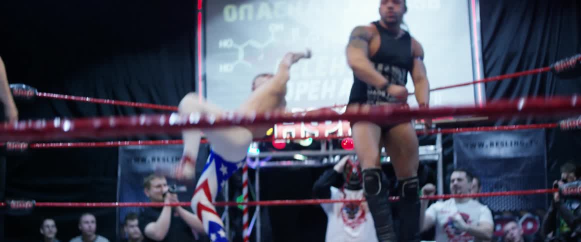 Two wrestlers fighting in a ring with spectators