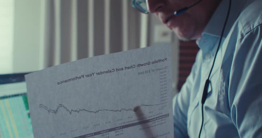 A man wearing headphones is using a pen to point to a paper that has a graph on it