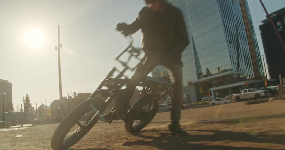 A biker whips donuts in in a gravel parking lot downtown