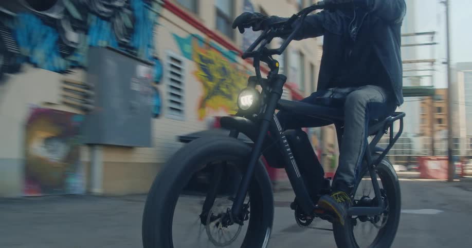 A man riding his electric bike down a graffiti covered alley