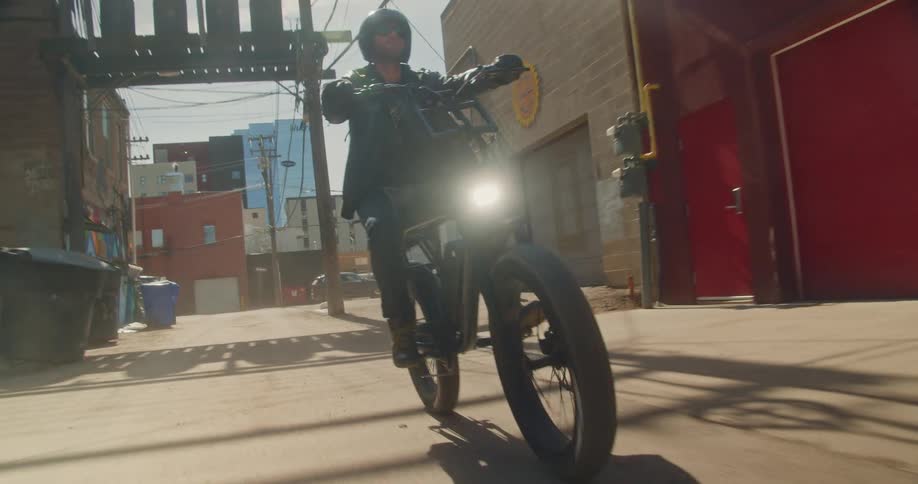 A man riding an electric bicycle in an alley on a sunny day