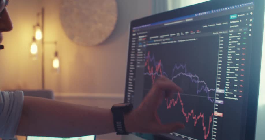 Man points at a stock chart on a monitor during a remote office call