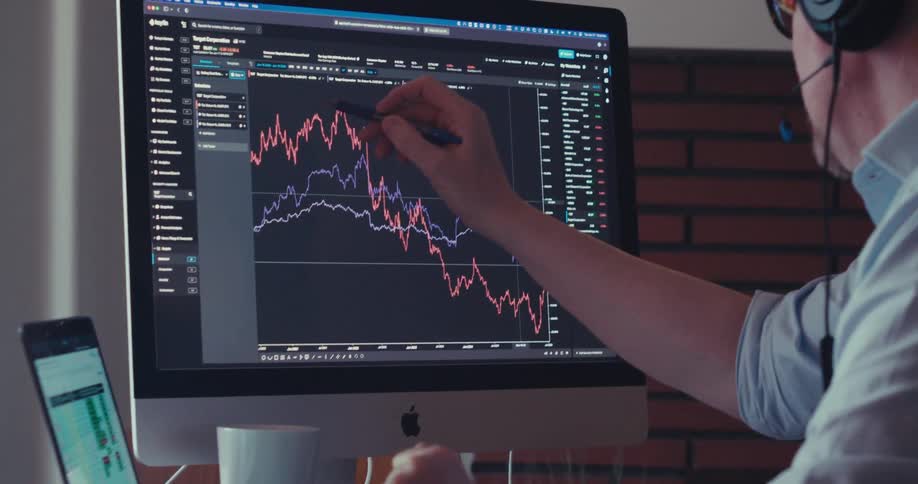 The man traces his pen across the bar graph