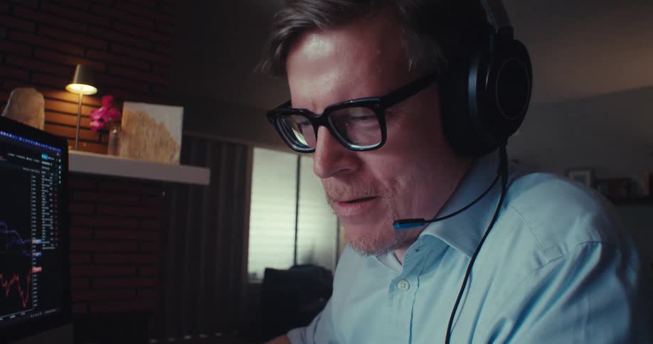 A man is on a call while analyzing stock charts on a desktop computer