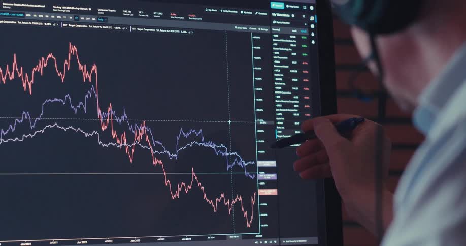 A man talks while pointing to graphs on his computer