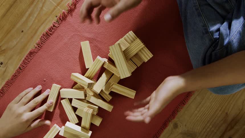 Four people playing a game with small piles of falling apart wood