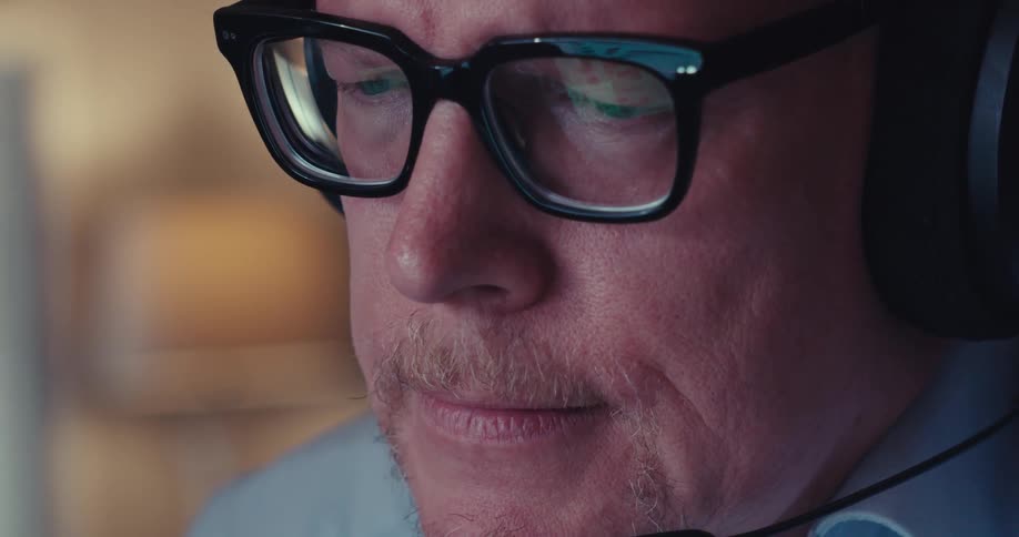 Man wearing a headset frowns while viewing his computer screen