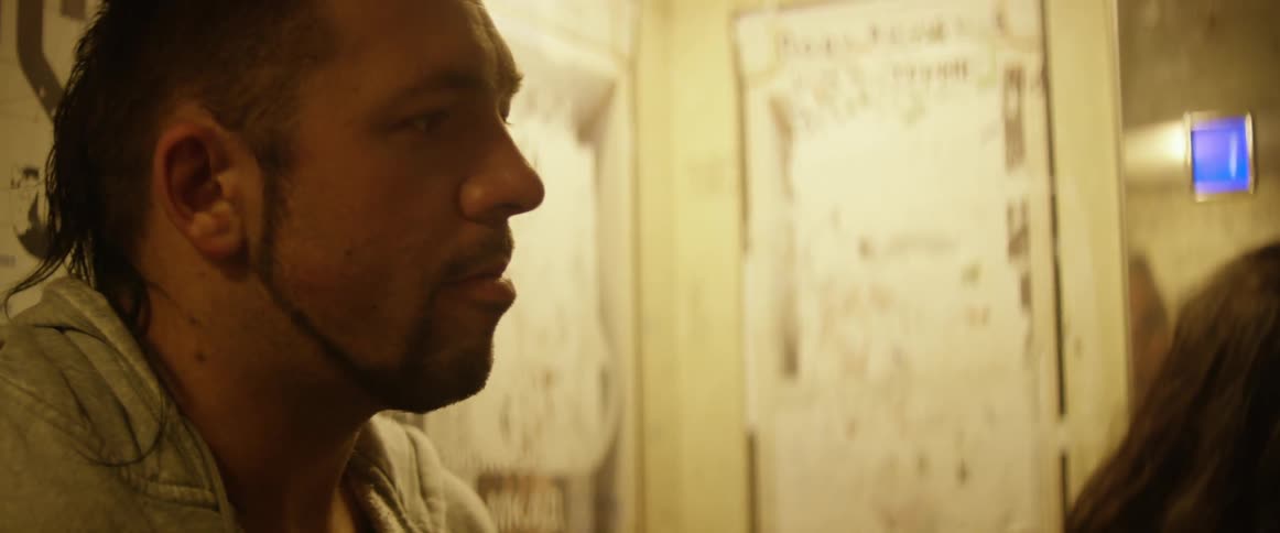 A man chews while leaning against a wall
