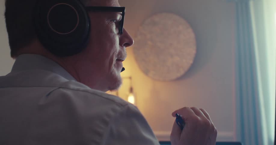 Man analyzes financial data on a multiple screens while wearing headphones