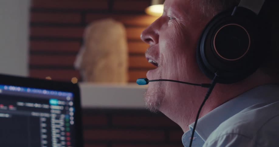 Man wearing a headset while sitting near a computer laughs