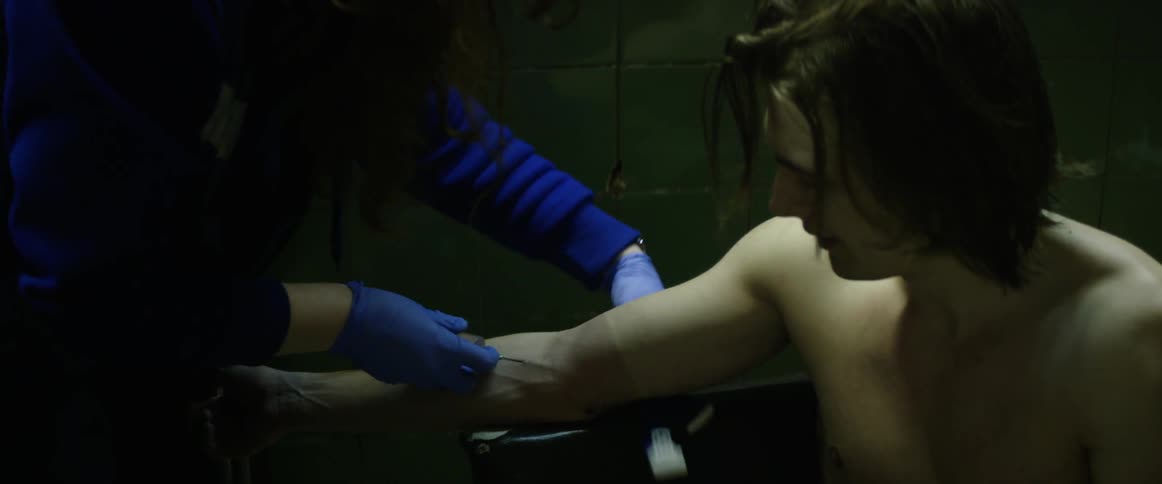 A woman inserts a needle into a man's arm