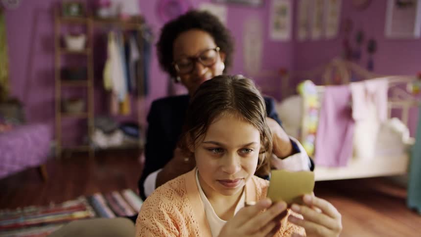 A mother is combing her daughters hair